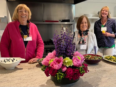 Three members of the garden club standing behind an arrangement of flowers