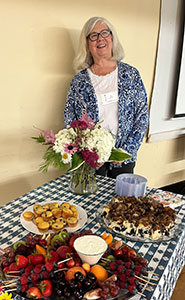 A woman standing near a table of food and flowers